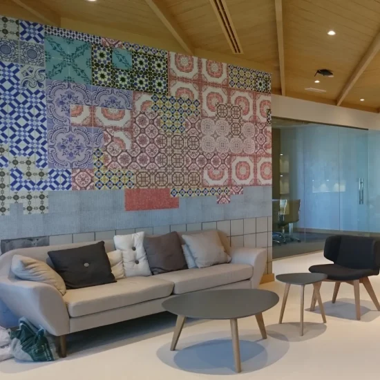 Factory office interior design in Dubai with a ceramic tile feature wall, neutral lounge seating, timber ceiling, and glass meeting room