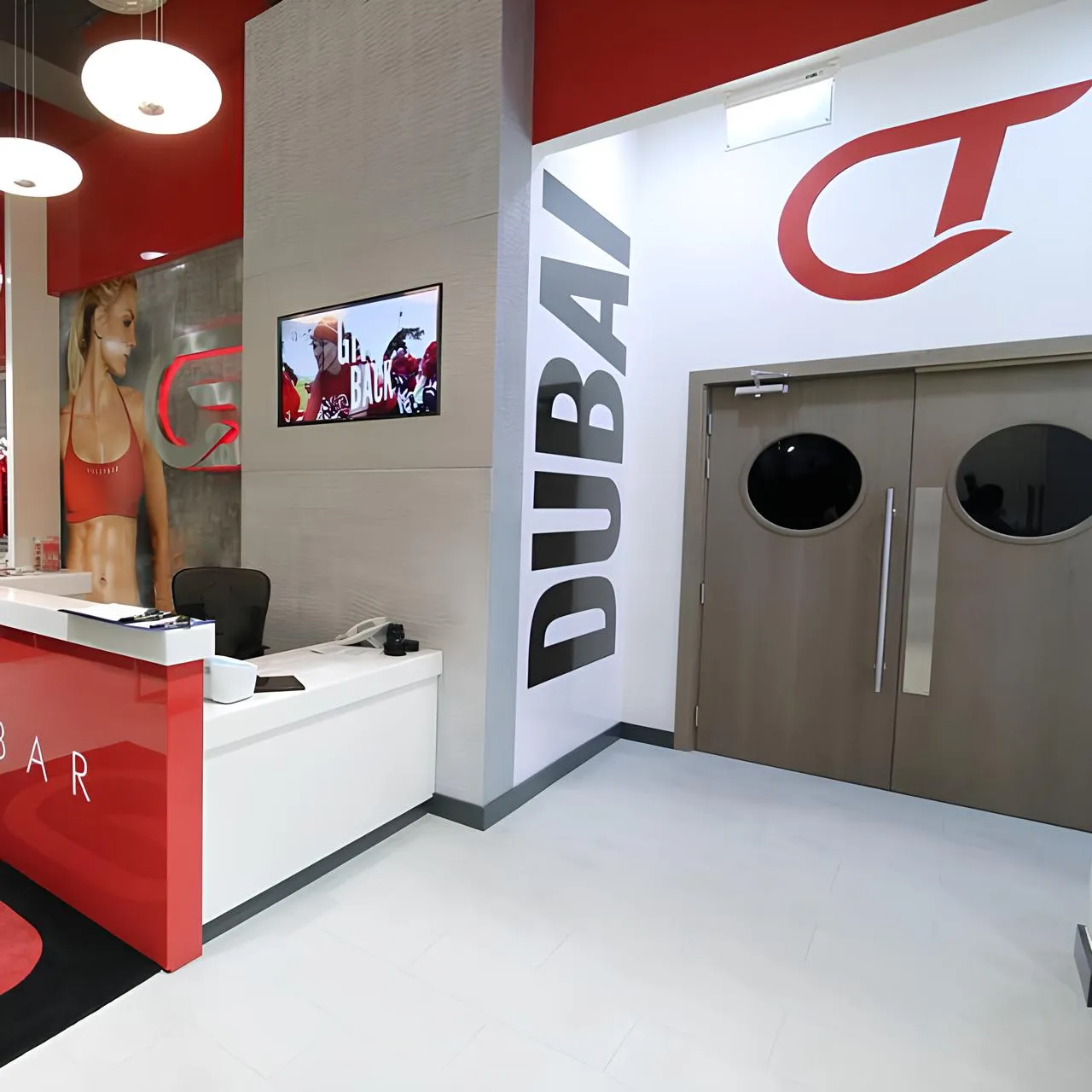 Dubai spin studio design with reception area, branded entrance doors, wall-mounted screen, and modern fitness studio graphics